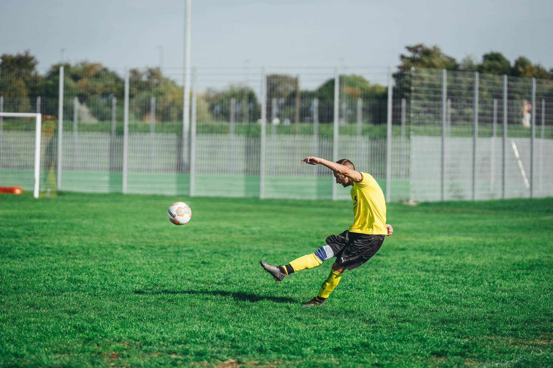 Soccer player in yellow jersey kicking ball